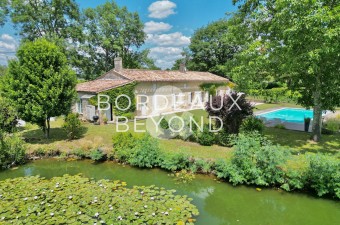Just 10 minutes from Saint-Émilion, this stunning single-story stone house has been completely renovated, offering a tranquil setting surrounded by vineyards and a pond.